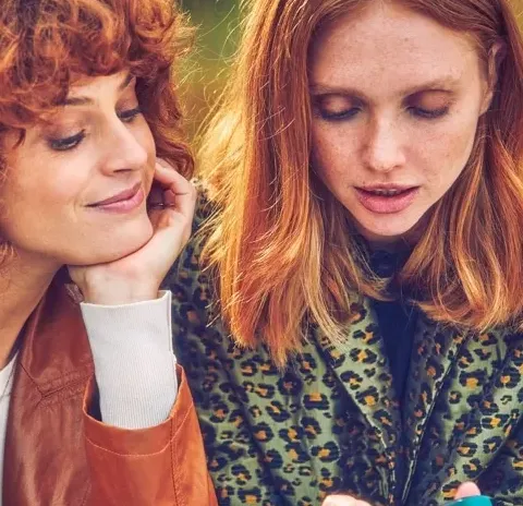 two redhead ladies looking at a device